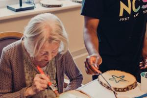 Volunteer from NCS Young People painting with an older lady at Borough Care’s Lisburne Court